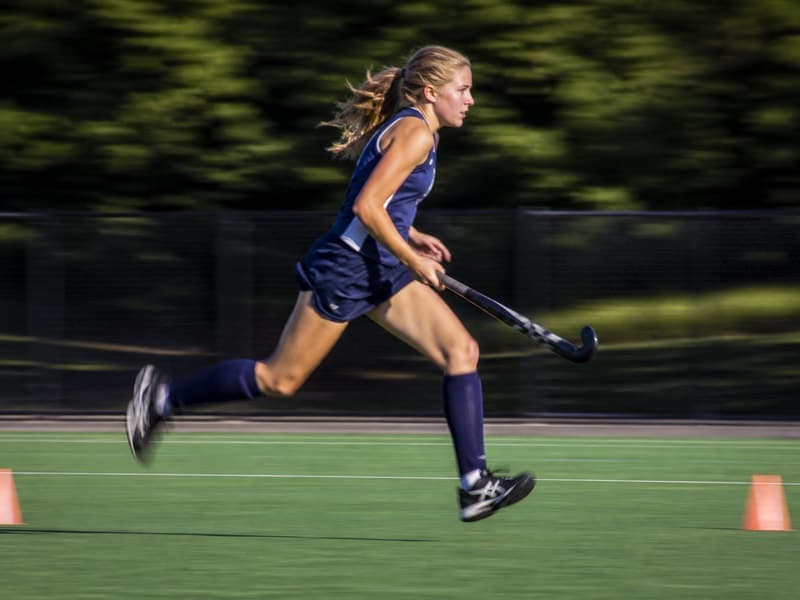 Jugadora de hockey corriendo con la bocha en la cancha